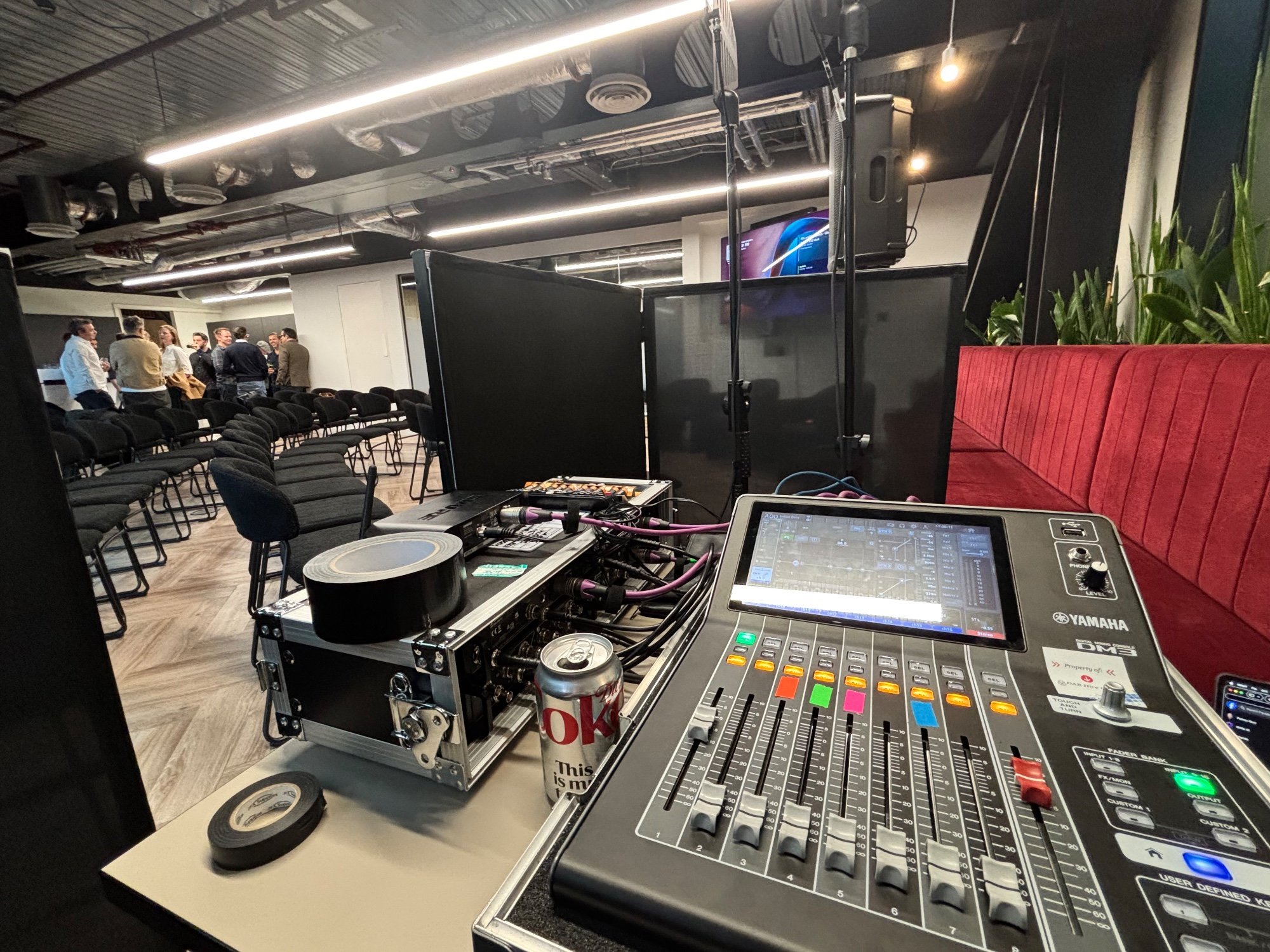 Digital mixing desk and a flight-cased stage box set up beside a seated talk space