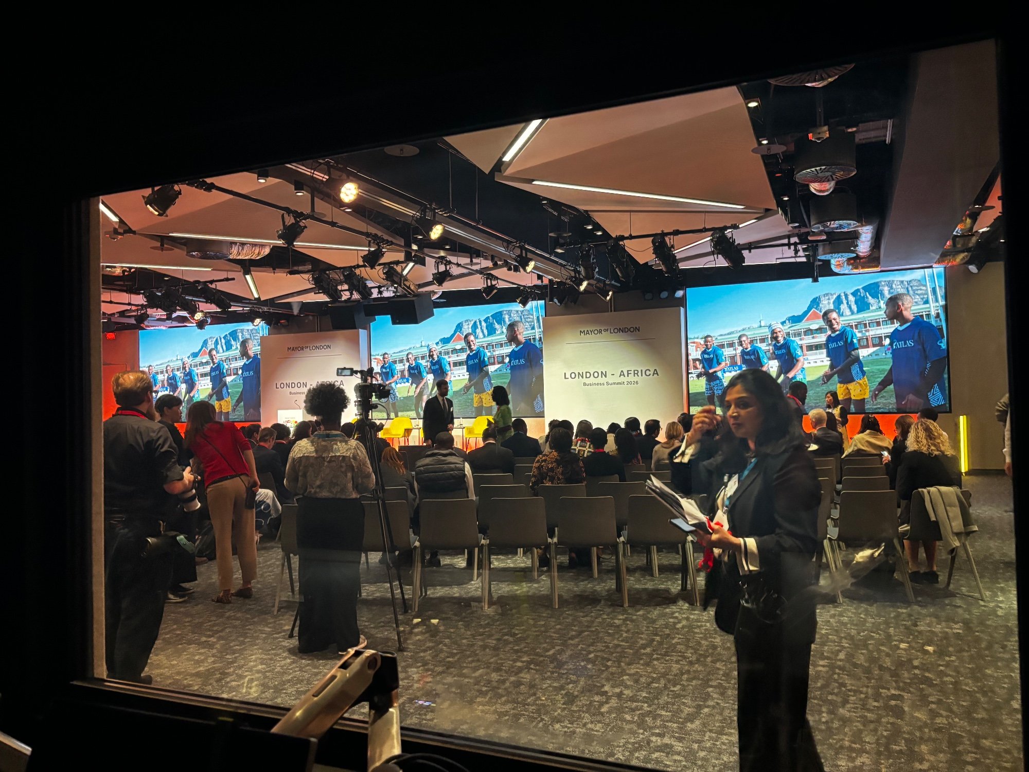 Conference stage with three large screens and an audience seated in front